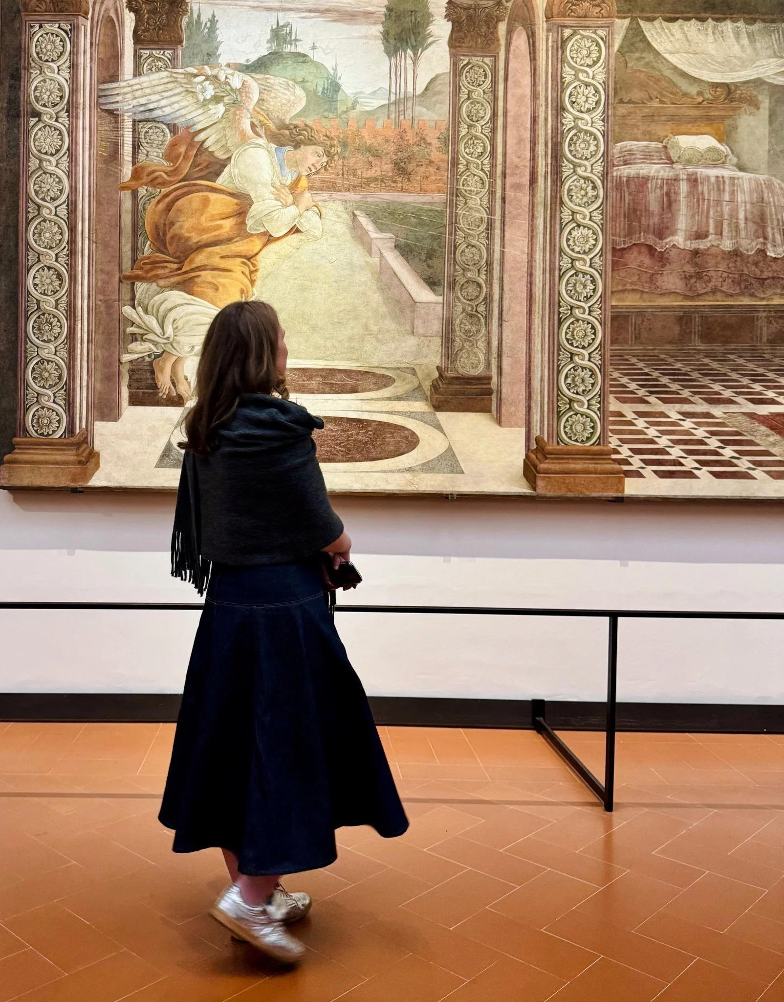 A woman looking at a large painting in an art gallery.
