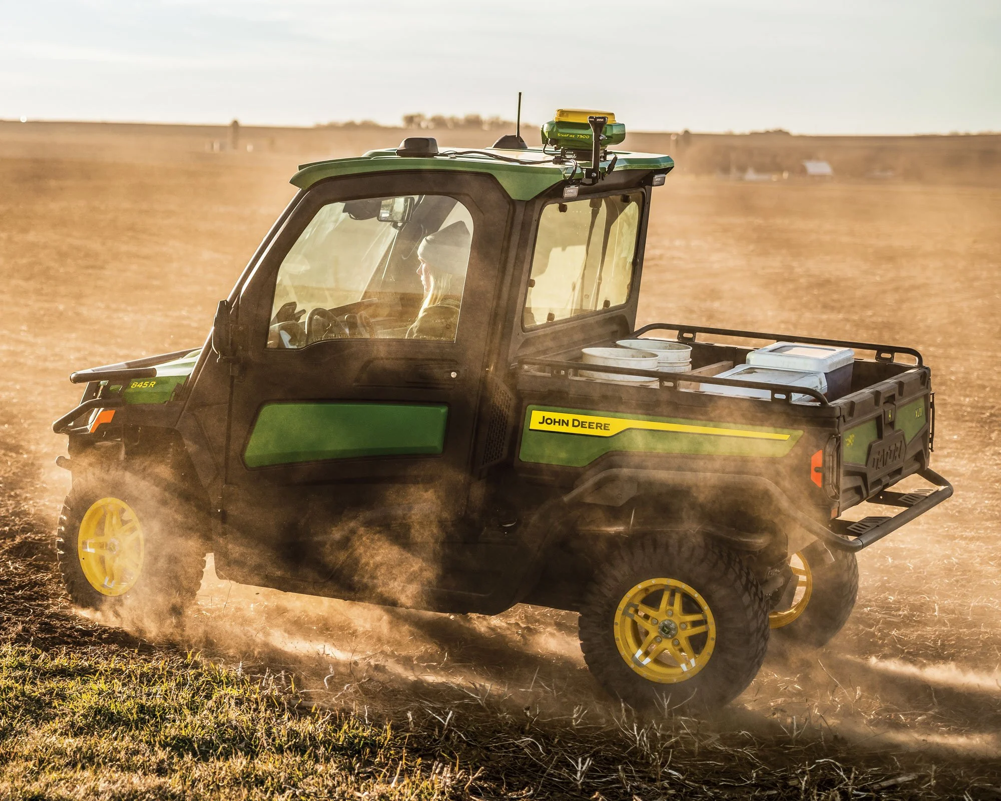 A green John Deere utility vehicle driving on a dirt field at sunset, Mapping Field Boundaries.