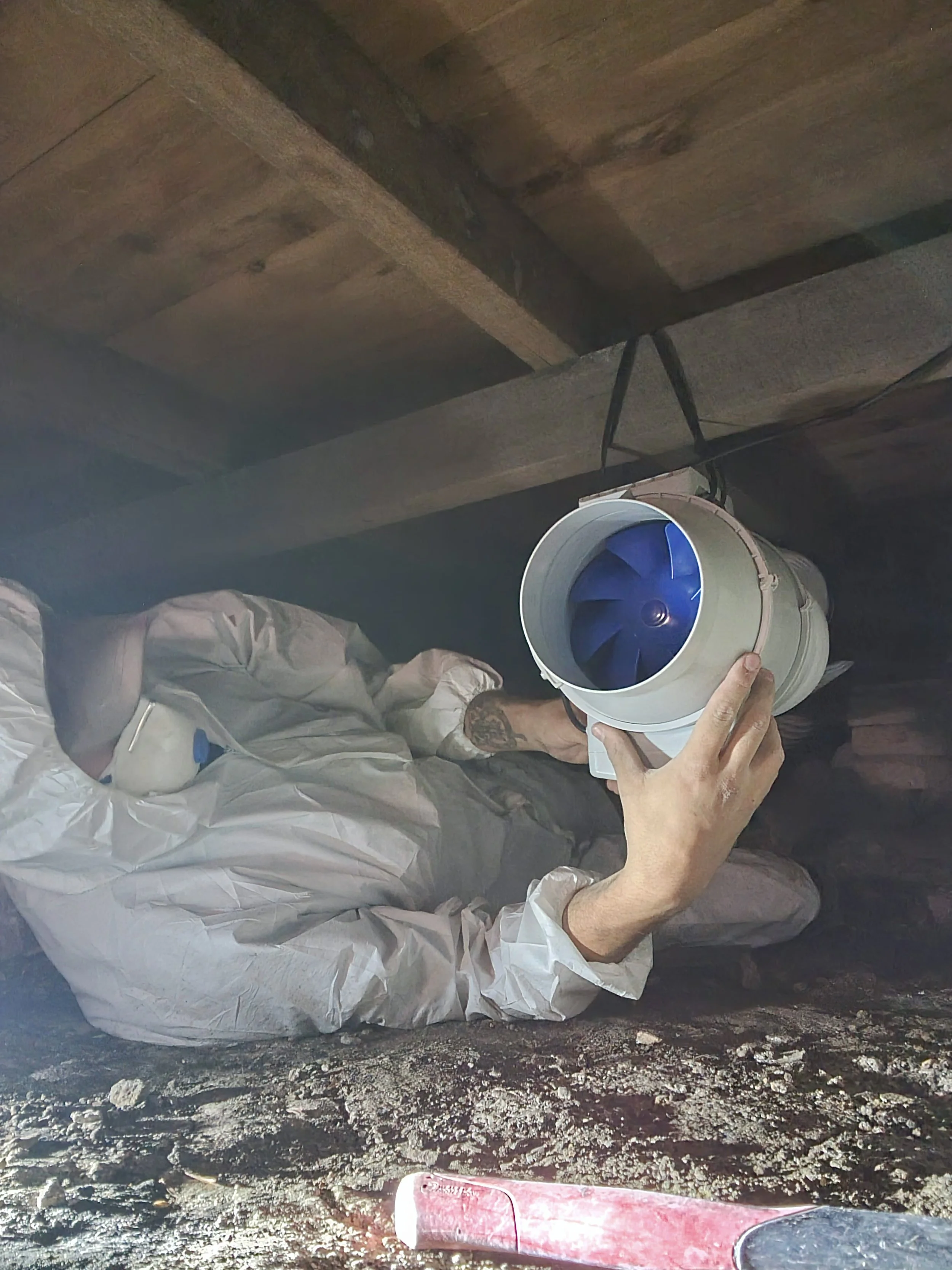 Person wearing a protective suit and installing a subfloor ventilation system in Sydney, NSW.