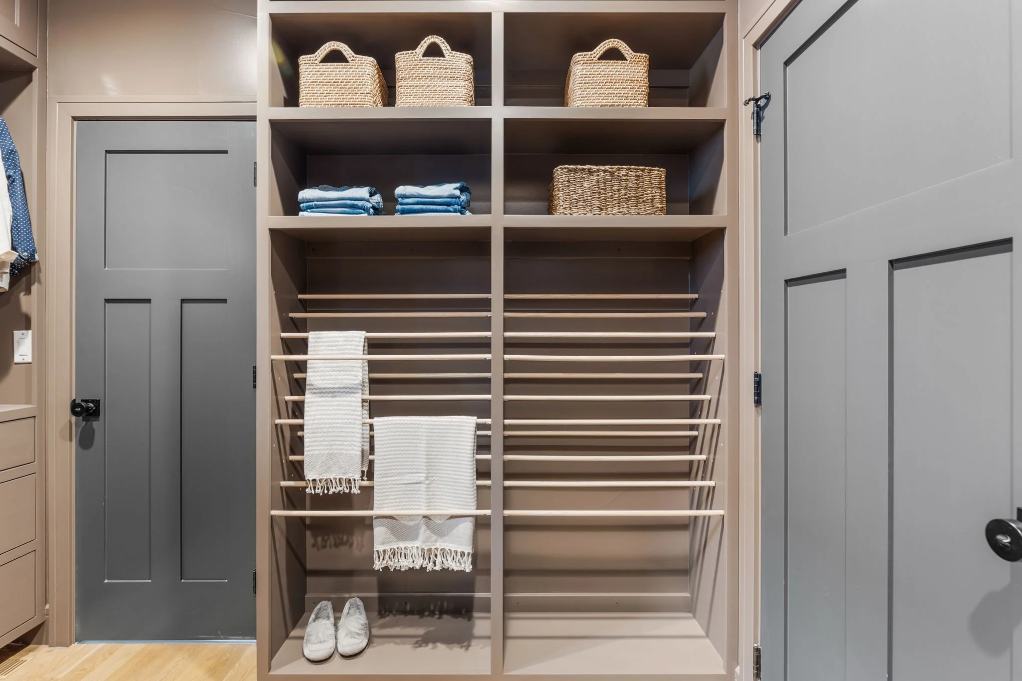Organized closet with shelves containing baskets, folded clothes, and towels, and shoe shelves at the bottom