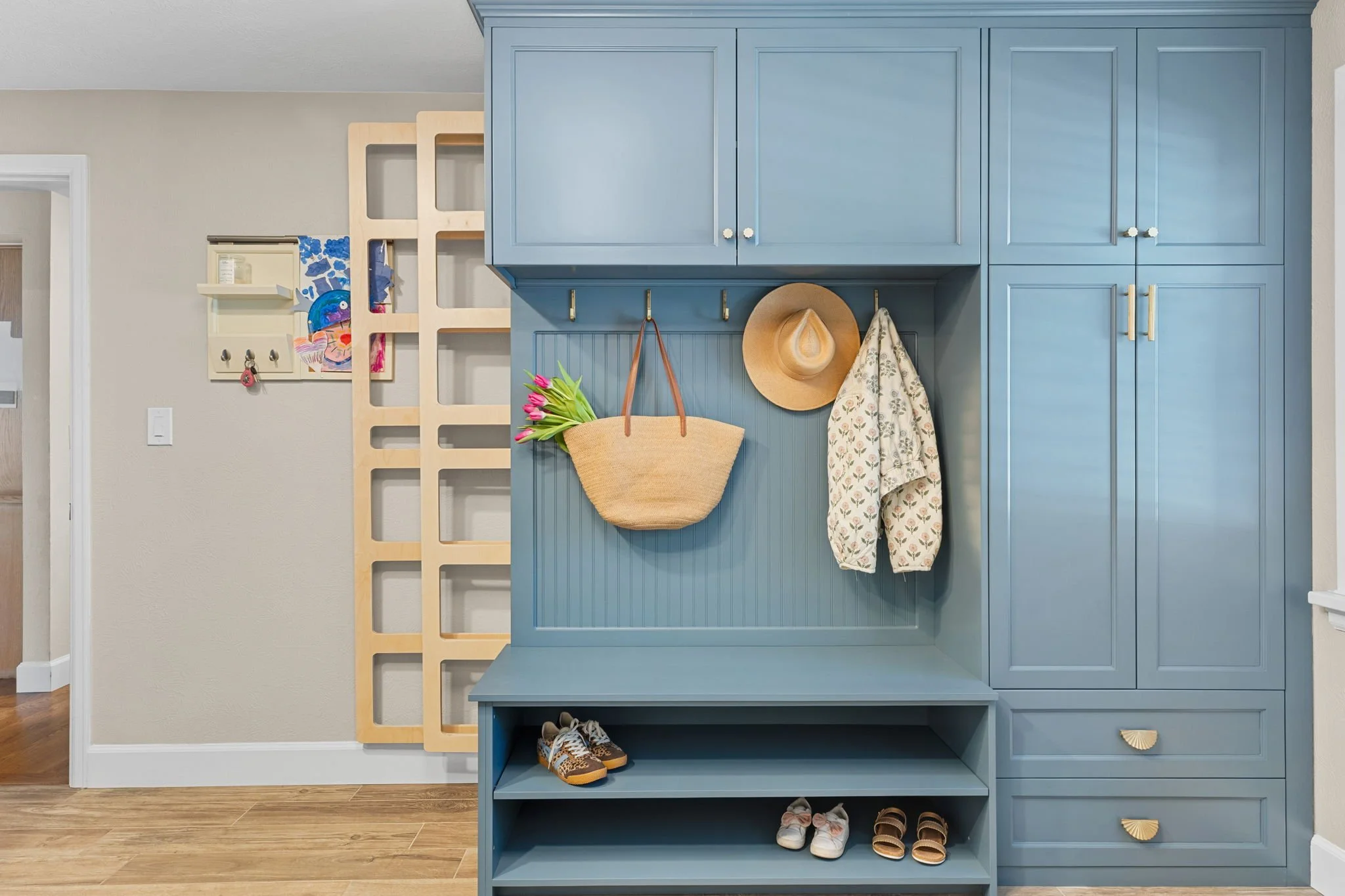 A Navy laundry bench unit with two slide retractable drying rack elegantly hidden behind bench and coat rack. 