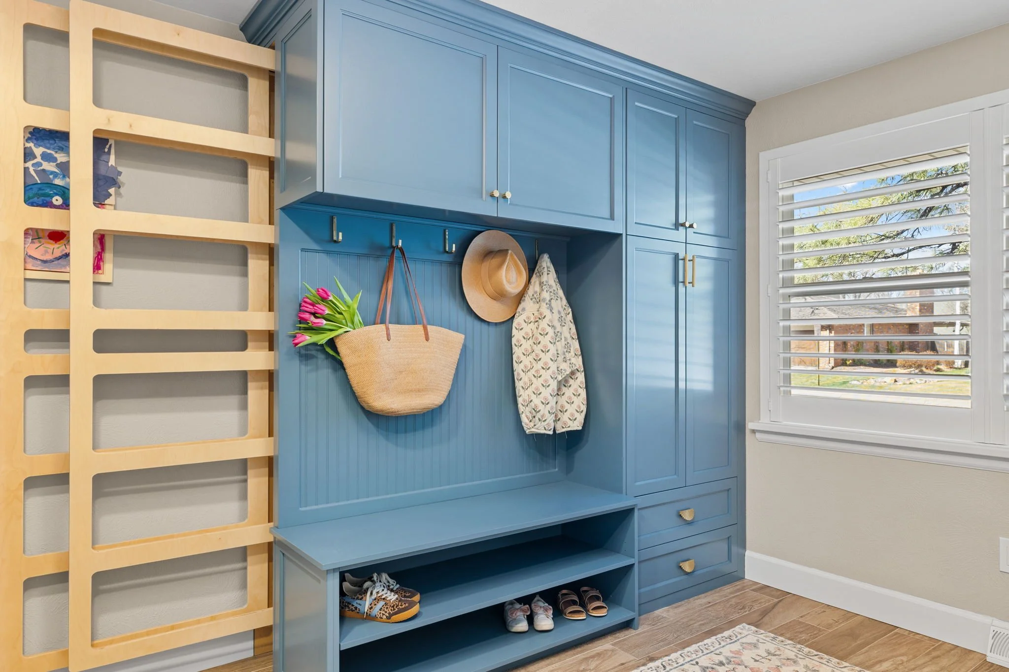 A Navy laundry bench unit with two slide retractable drying rack elegantly hidden behind bench and coat rack. 