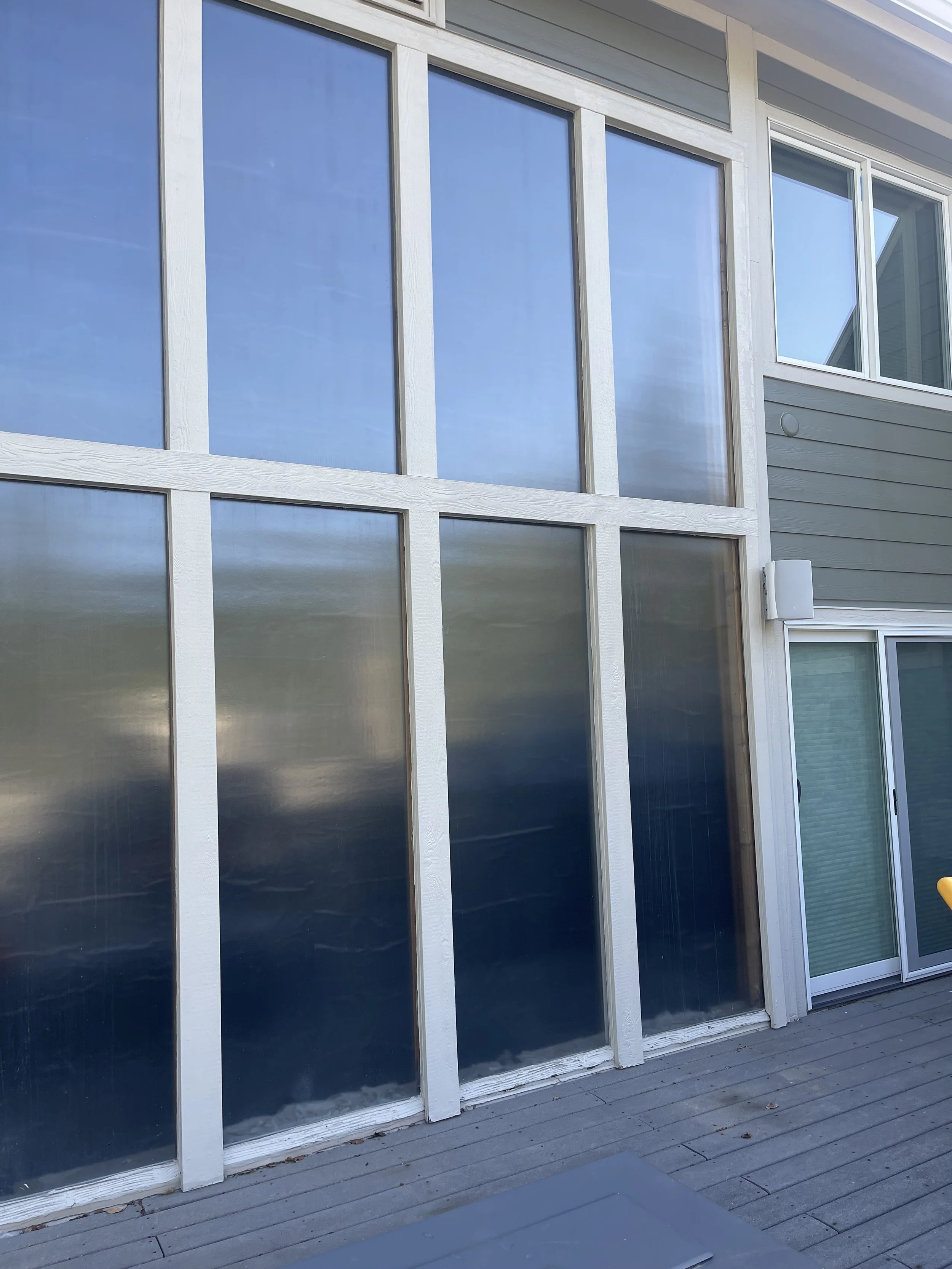 Exterior of a modern house with large glass windows and a wooden deck.