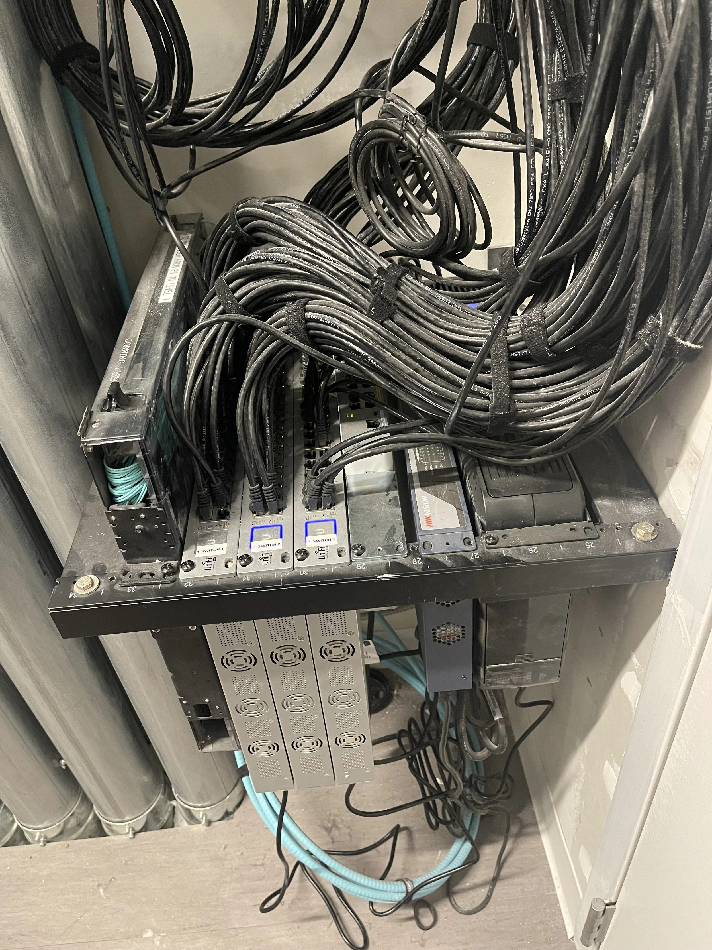 Close-up view of a server or networking equipment with numerous black cables connected to it, situated on a metal rack or cabinet.