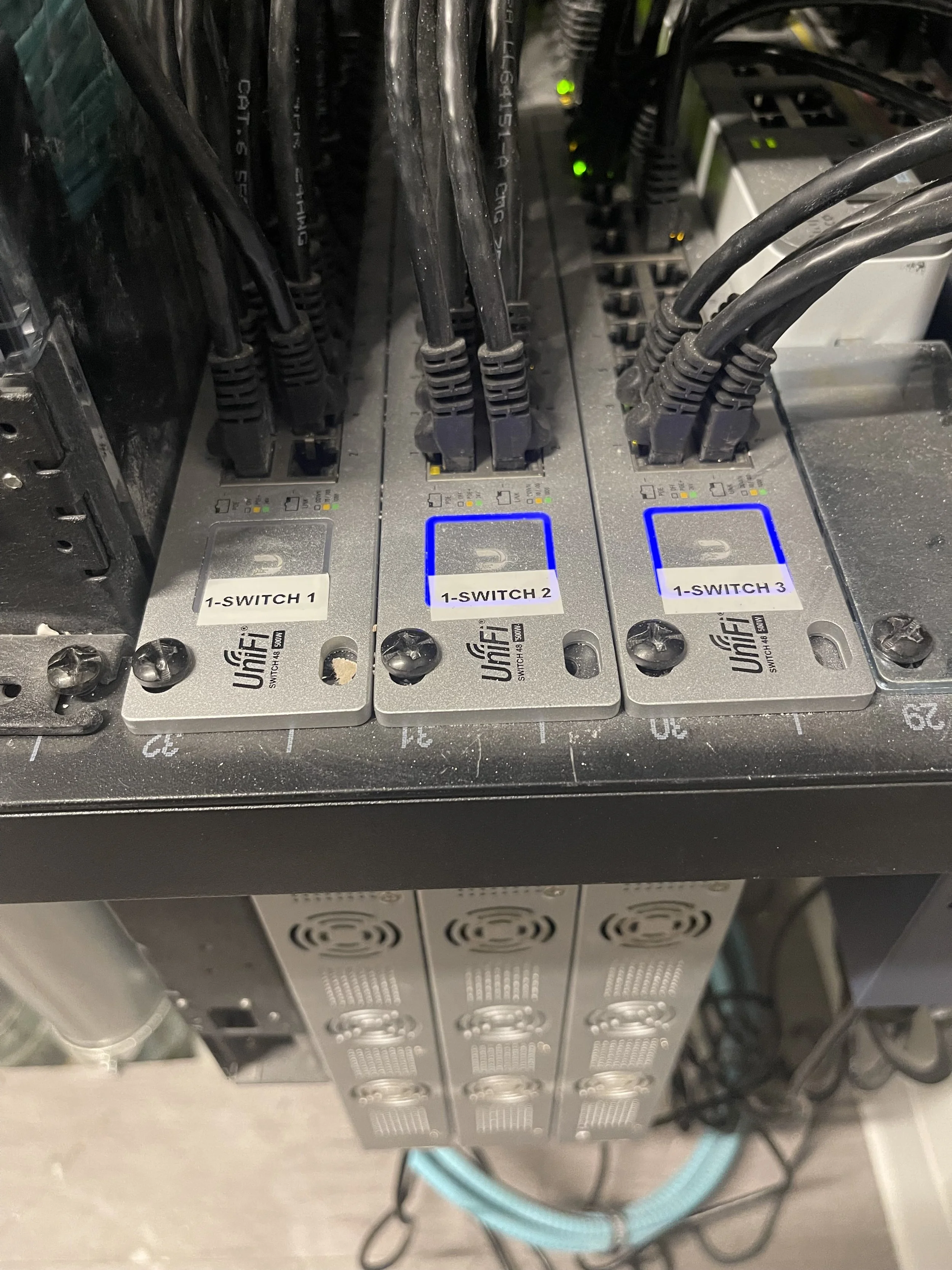 Close-up of three UfiFi network switches labeled 1-Switch 1, 1-Switch 2, and 1-Switch 3, with network cables plugged into them.
