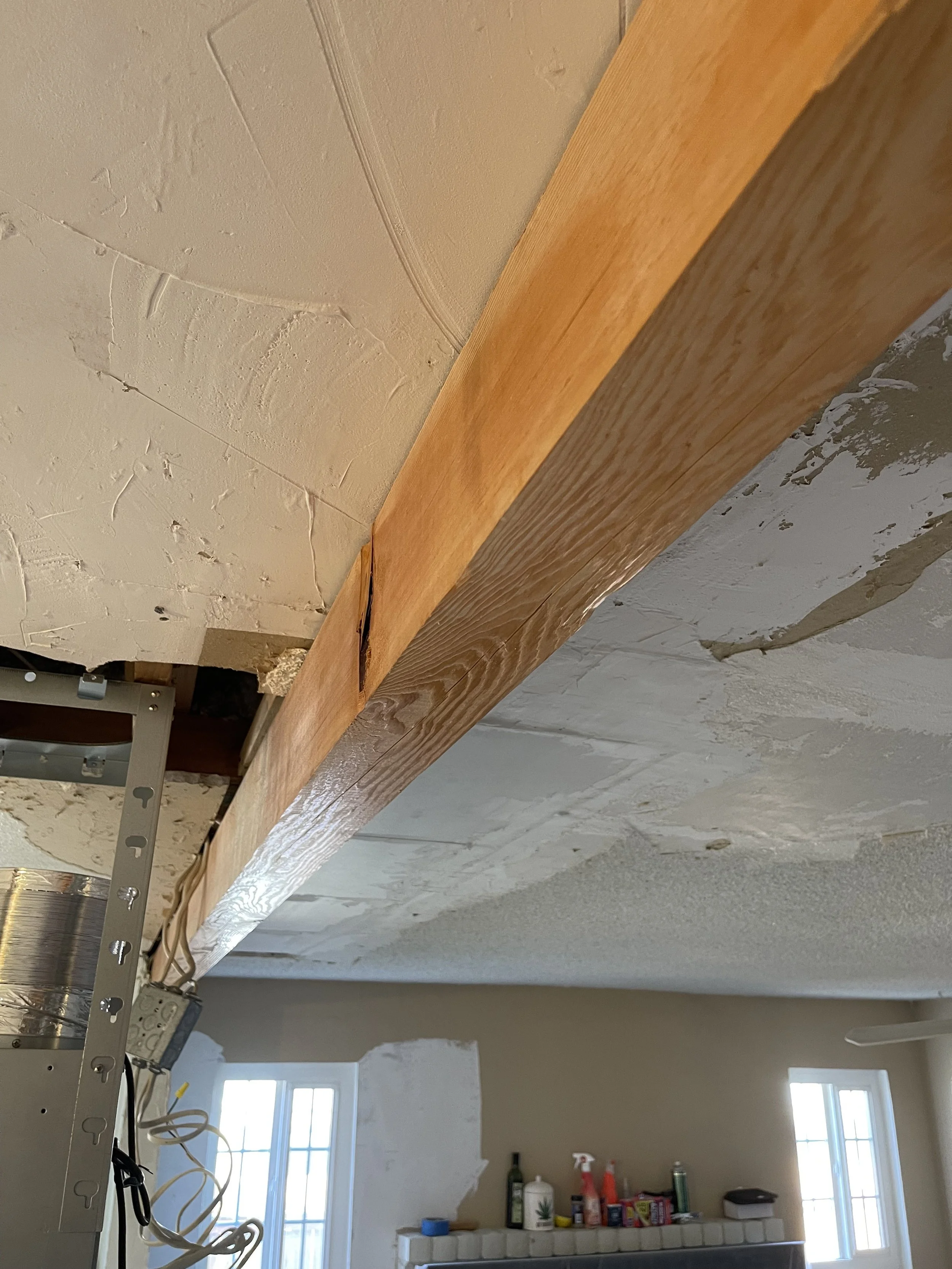 Part of a ceiling with some patches and a wooden beam installed