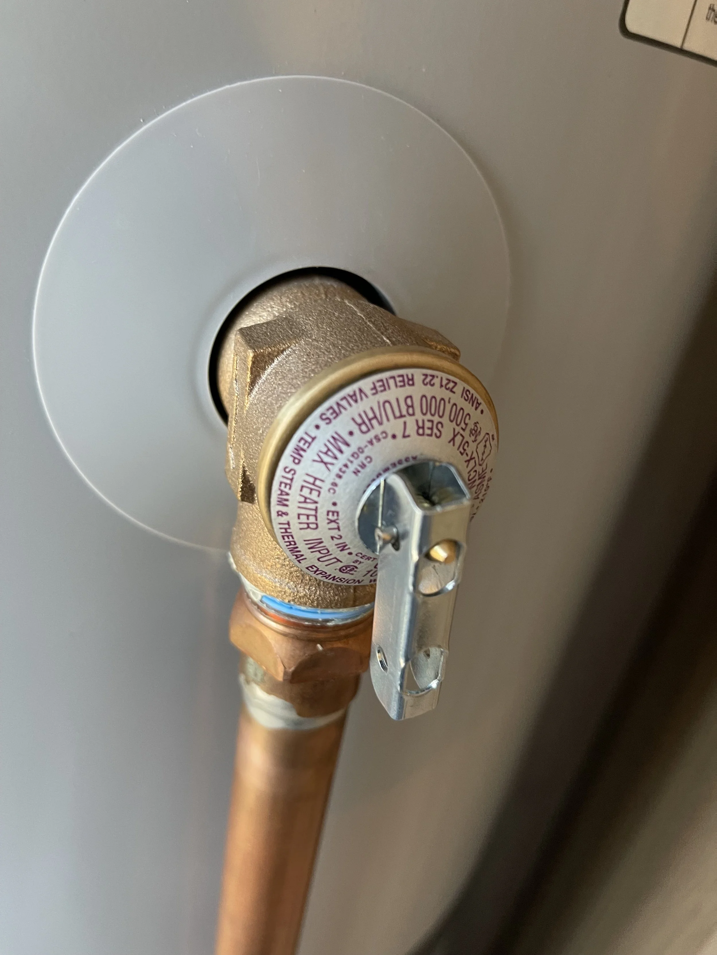 Close-up of a boiler pipe with a brass valve attached to it.