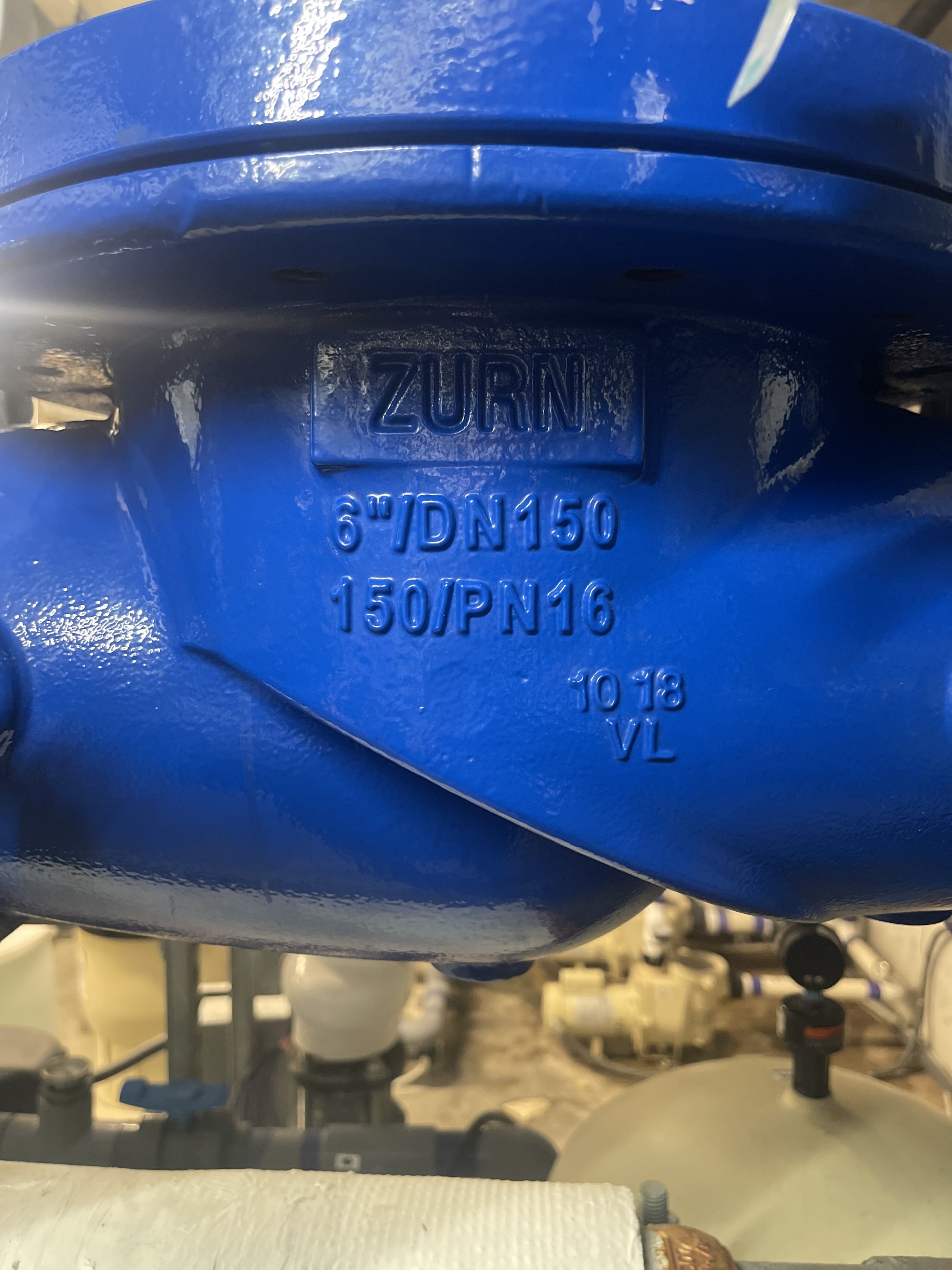 Close-up of a blue industrial valve with embossed markings reading 'ZURN 6" DN150 150/PN16 10-18 VL'.