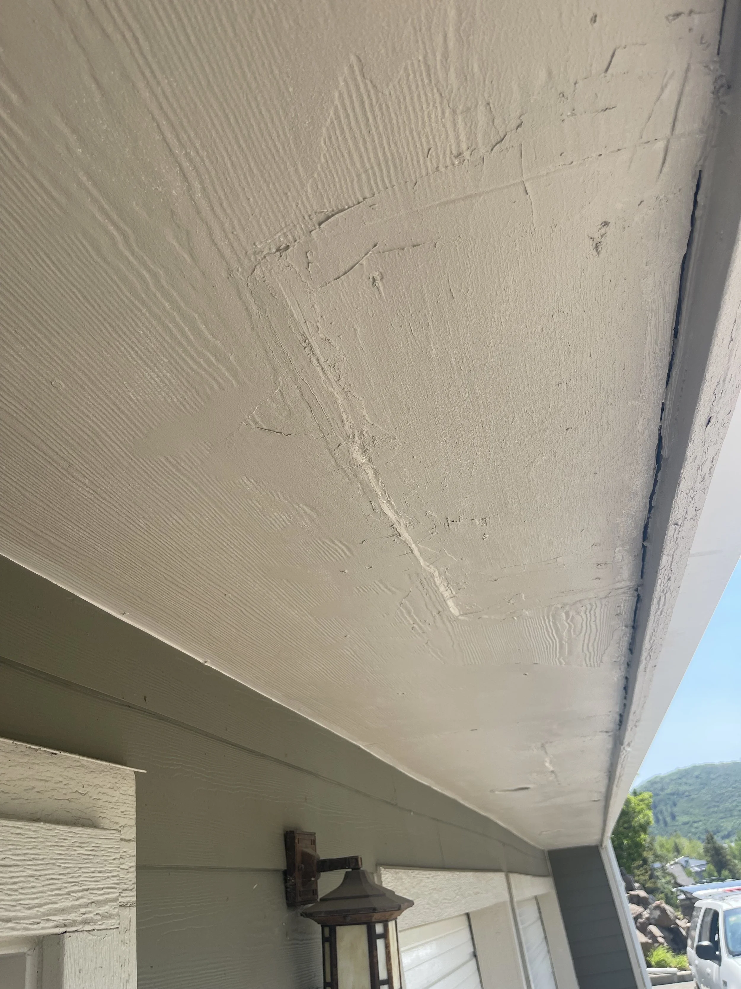 Cracked and peeling paint on an underside of a house soffit or eaves.