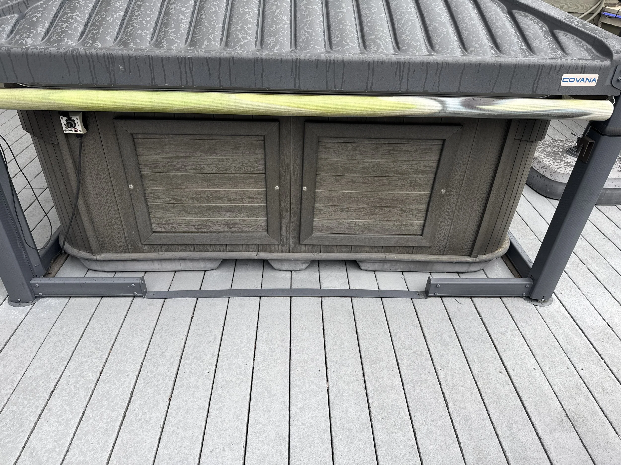 Outdoor hot tub with a weathered wooden exterior on a gray wooden deck.