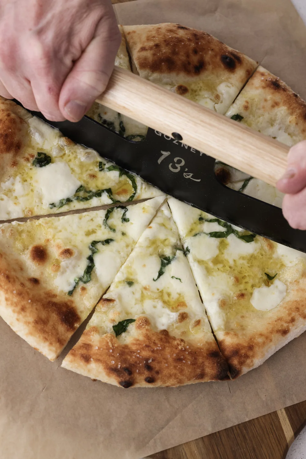 Slicing a fresh pizza with a Thirteen's cutter