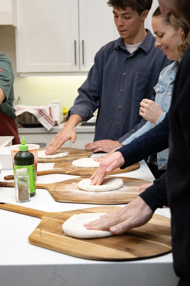 Hands shaping dough at a pizza class