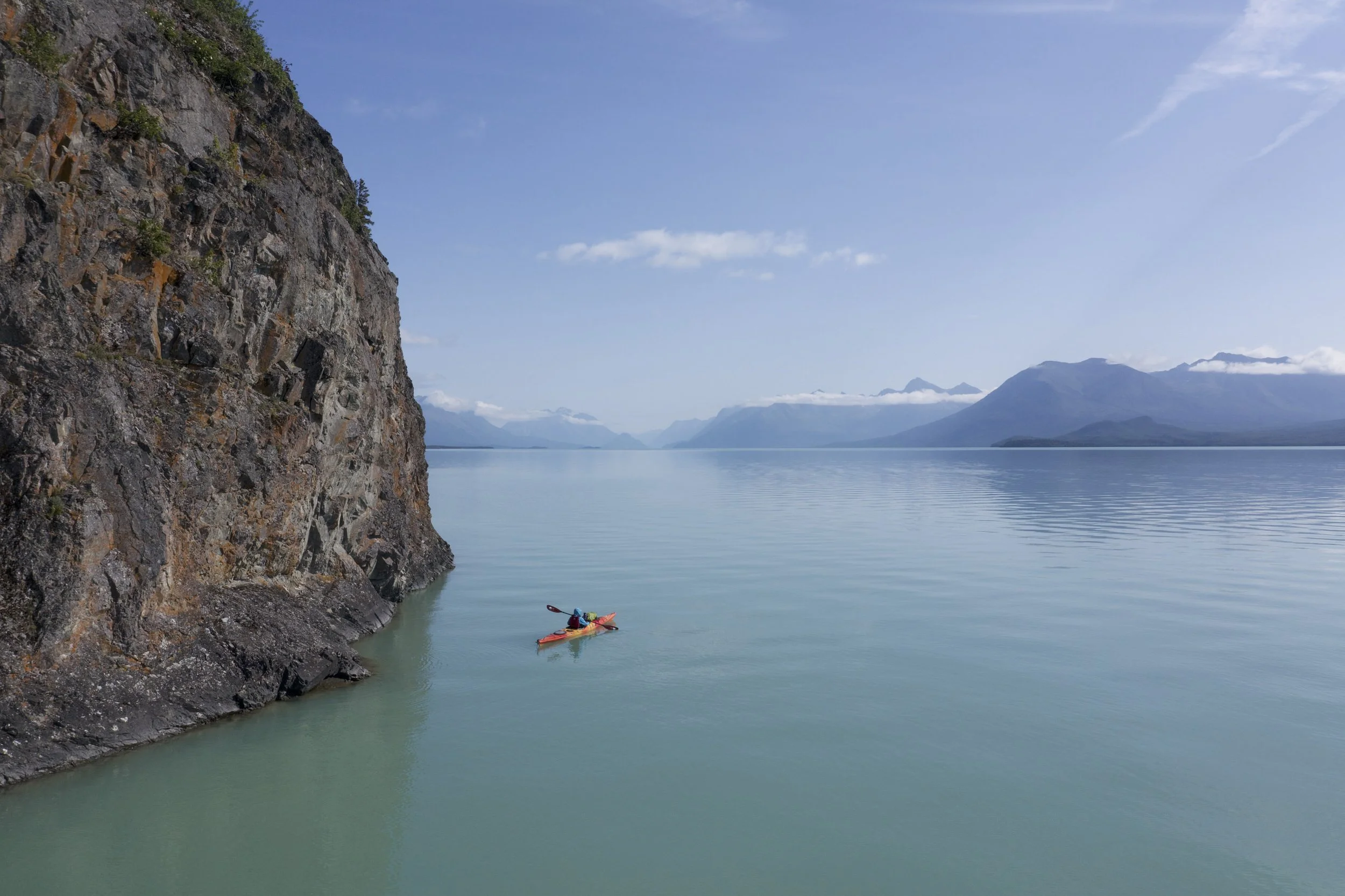 Kayaker paddling Lake Clark with views of Chigmit Mountain