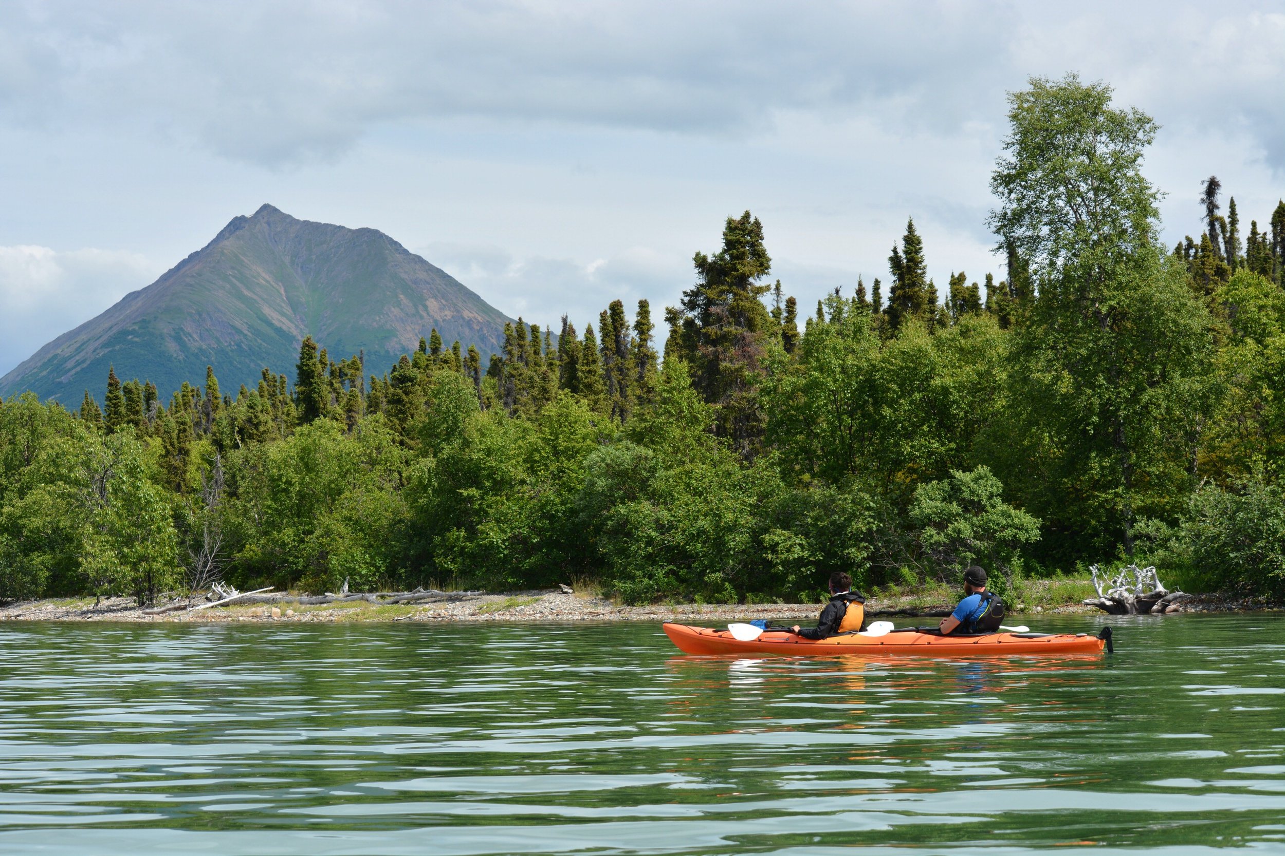 Kayakers paddling in Lake Clark National Park with views of Tanalian Mountain