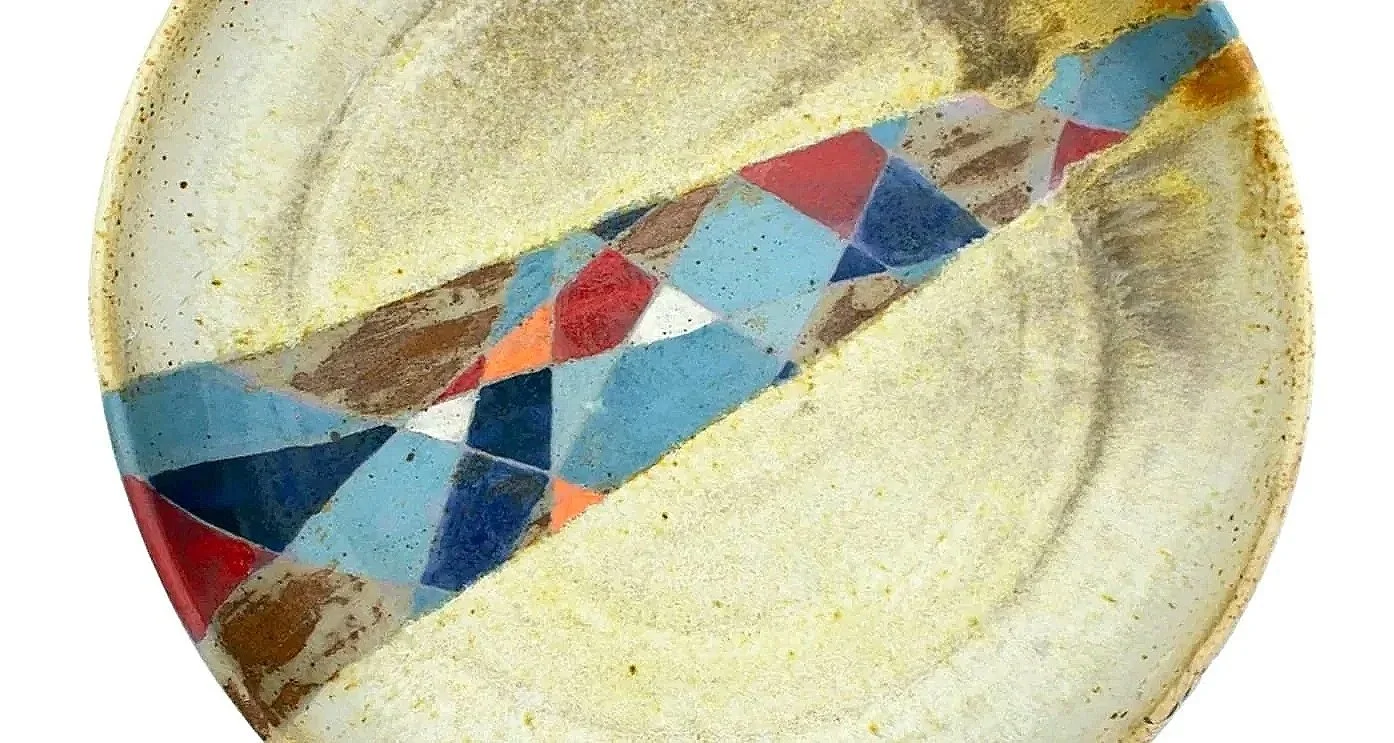 Close-up of a painted egg with an abstract, colorful geometric pattern inside a pale yellow shell.