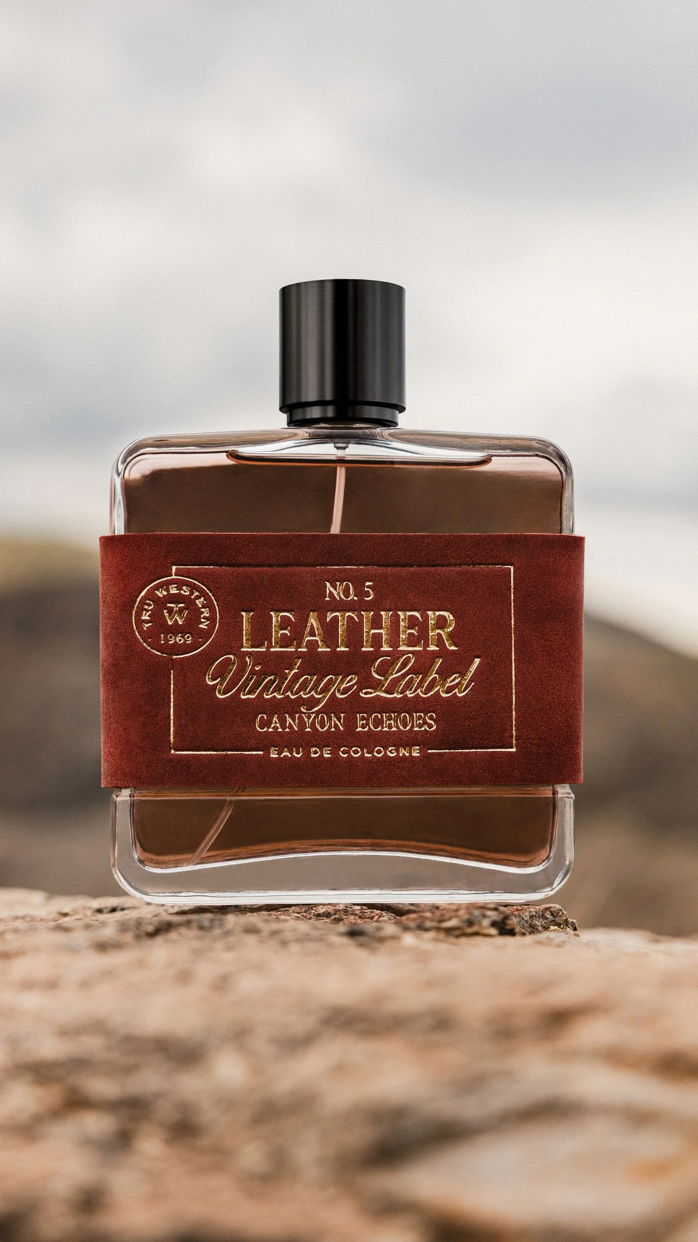 No. 5 Leather Vintage Label: Canyon Echoes standing on a sunlit rock against a pale desert sky, its red suede label lit.