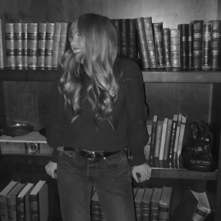 Jessie Roeker, creative director, black and white portrait by a bookshelf