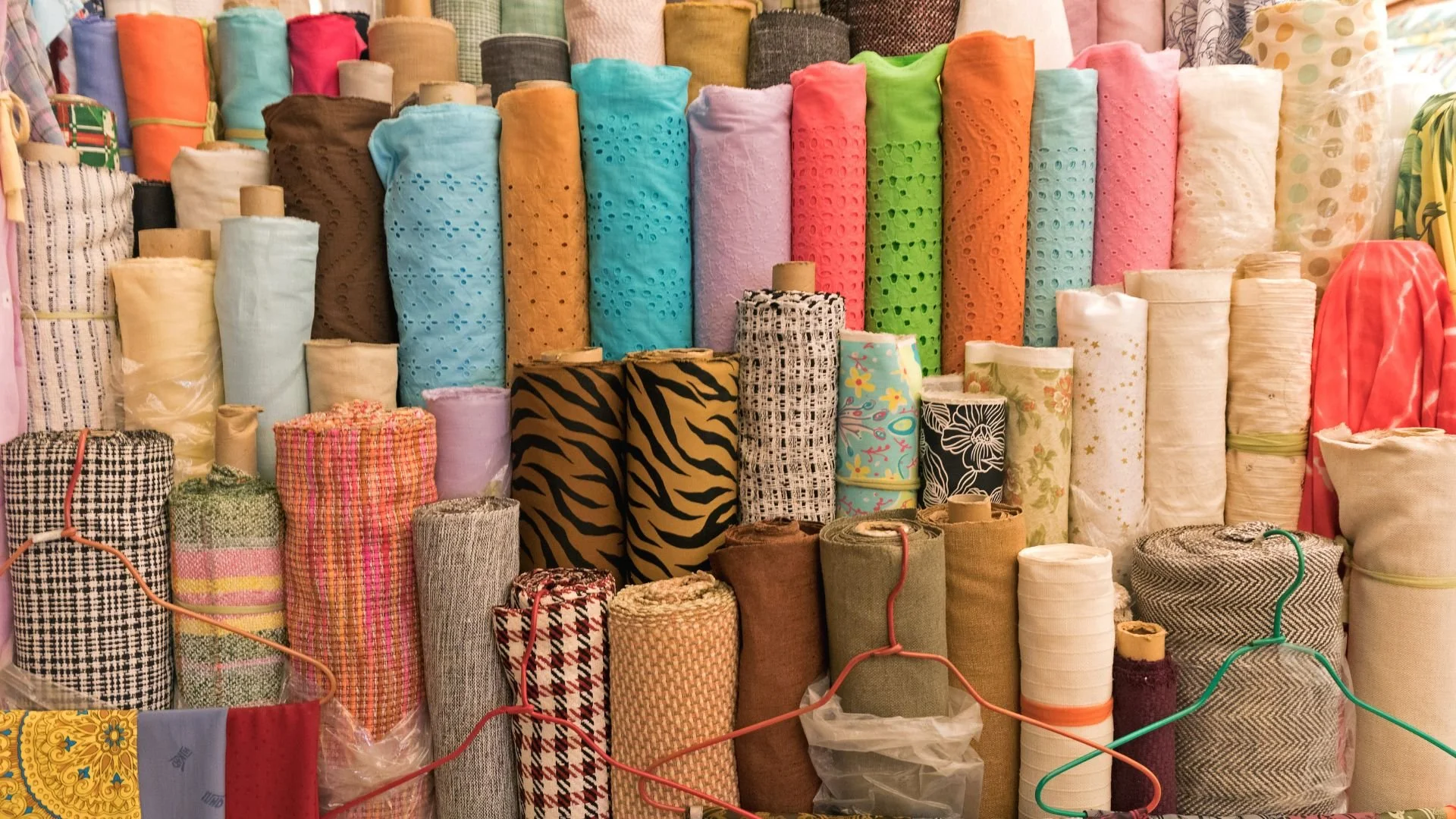 A display of colorful fabric rolls arranged vertically on shelves in a store.