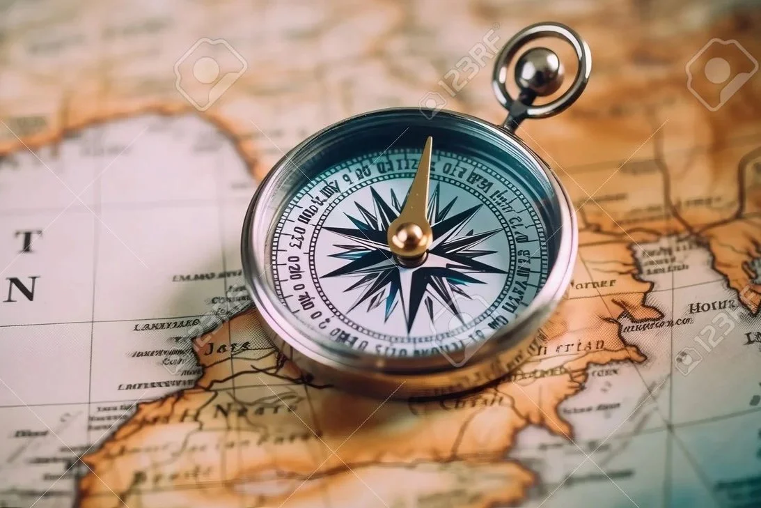 A silver compass with a black and white face showing north, placed on an old map of the western United States.