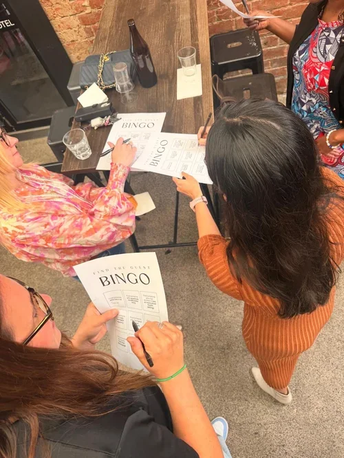 Four women playing bingo at a table in a casual indoor setting.