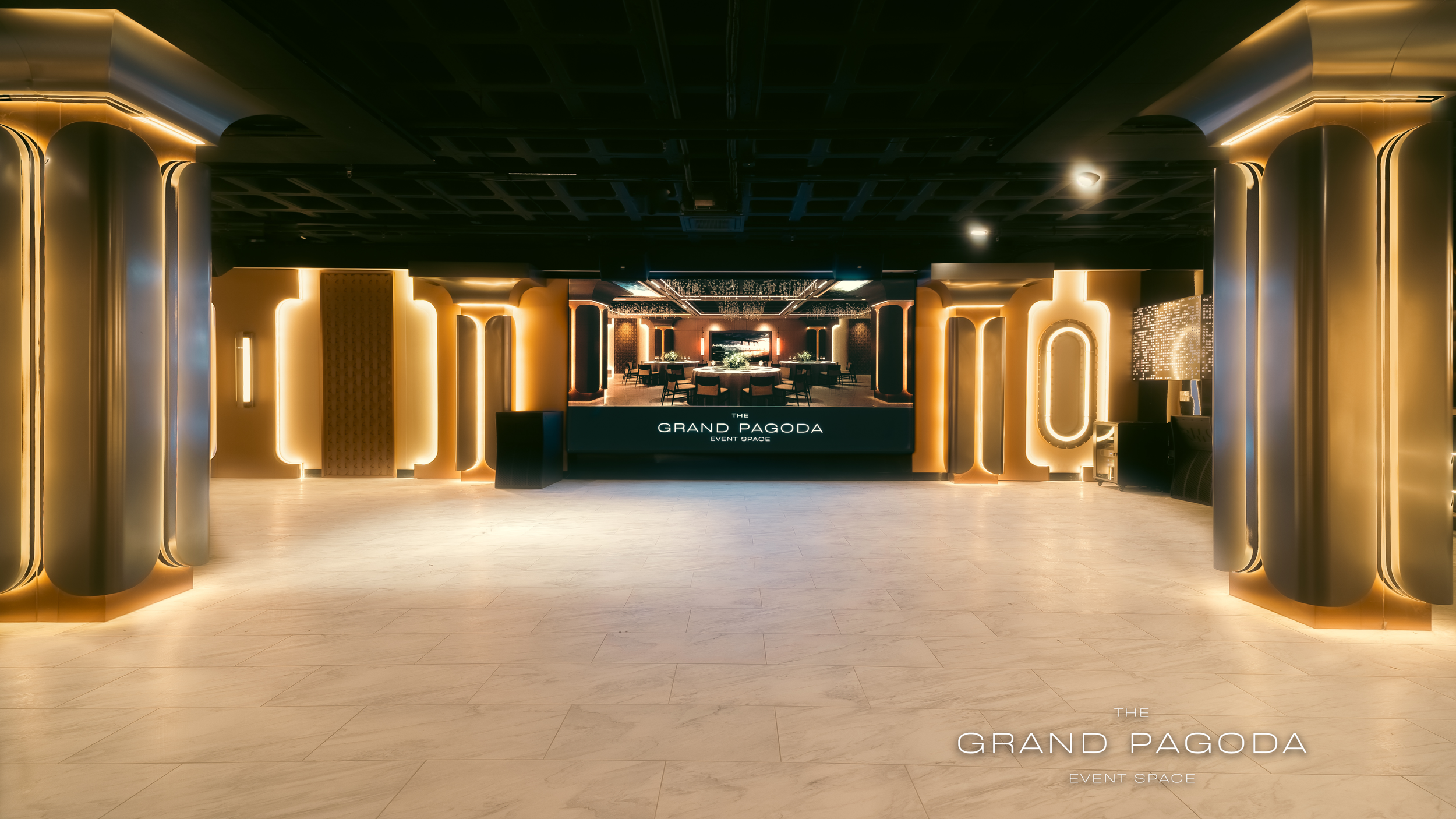 Elegant event space with a modern design, featuring warm lighting and a large display that reads 'The Grand Pagoda Event Space,' with tables and chairs set for an event.