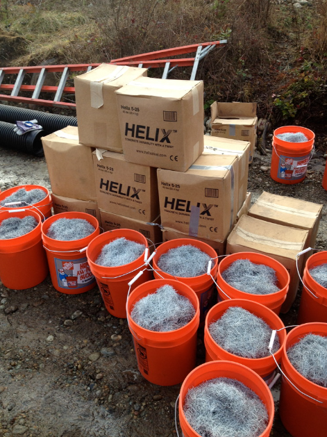 Construction site outdoors with boxes of supplies and orange buckets filled with steel wool scrubbers.