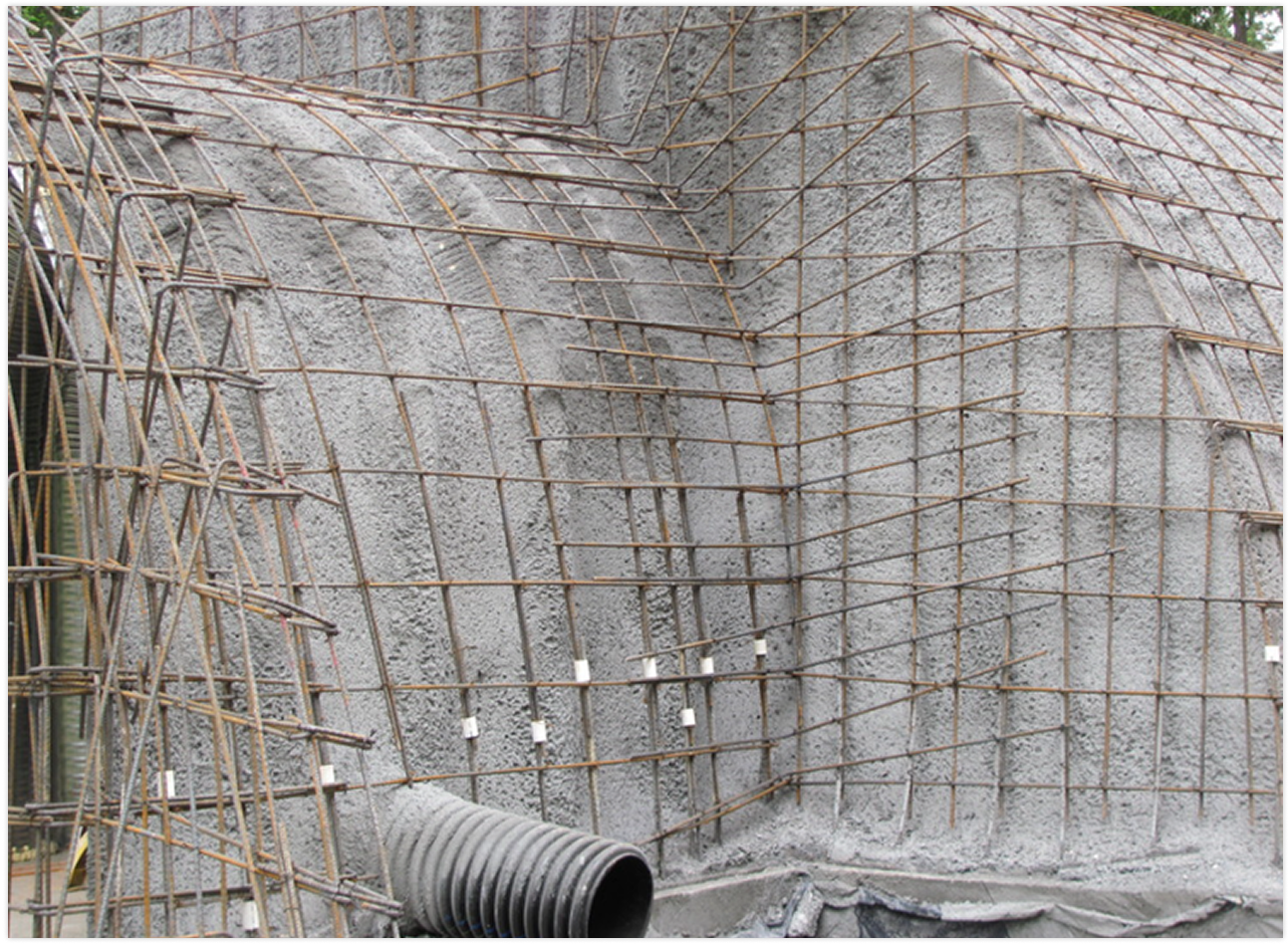 Construction site with concrete wall reinforced with steel rebar and a flexible pipe at the bottom.