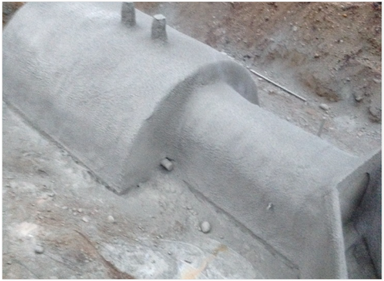 Close-up of a concrete utility box or cover on a construction site with dirt and gravel around it.