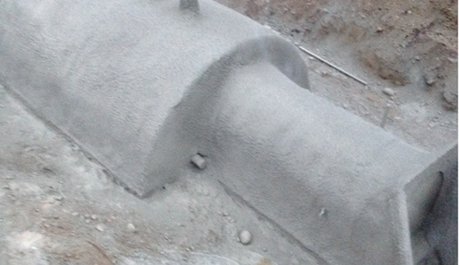 Close-up of a concrete curb or sidewalk with dust and small debris around it.
