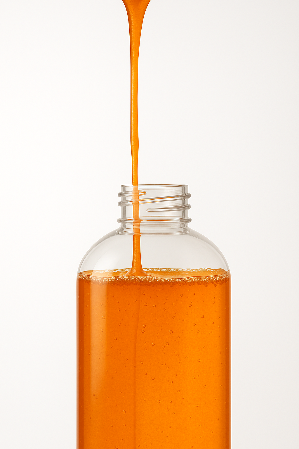 Orange detergent liquid being poured into a clear plastic bottle with a white background.