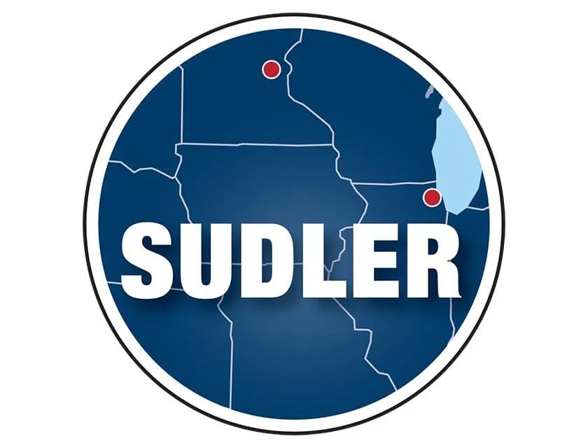 A circular graphic featuring a map with the state of North Dakota marked with a red dot, and parts of surrounding states. The word 'SUDLER' is prominently displayed in white capital letters across the center.