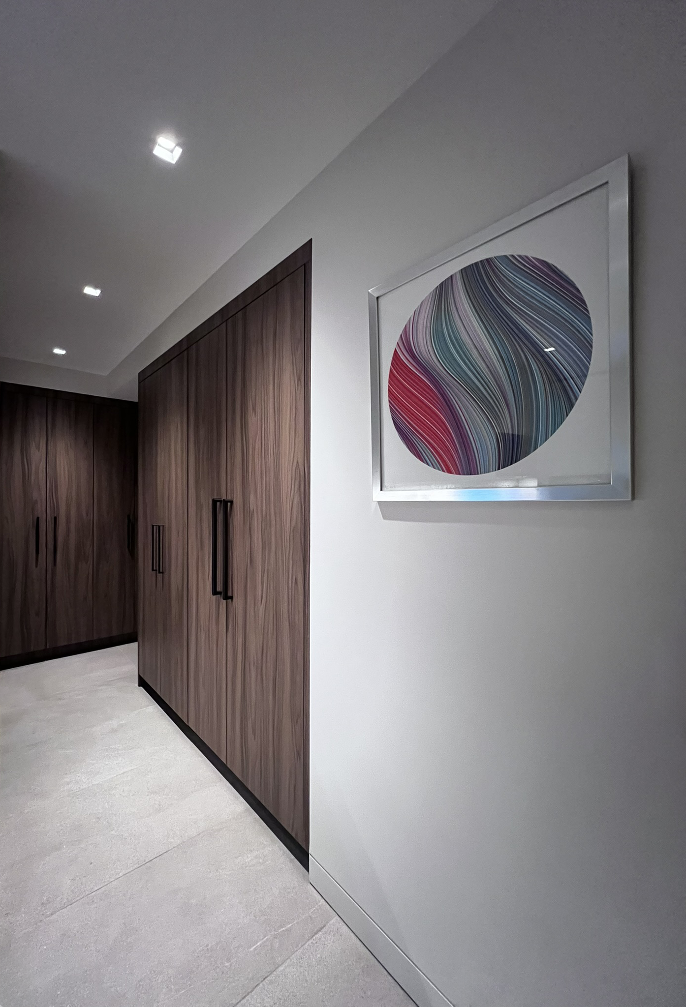 Interior hallway with custom wood cabinets and an abstract artwork on the white wall.