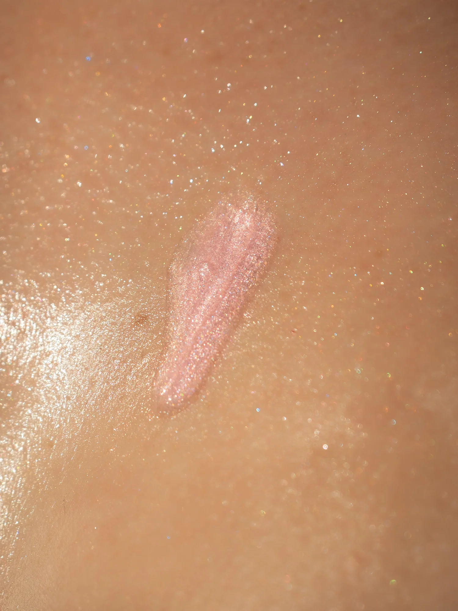Macro close-up of the pink shimmer oil on skin, fine sparkle catching the light