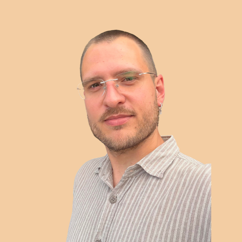 A man with short hair and glasses wearing a striped shirt, looking at the camera with a neutral expression, against a beige background.