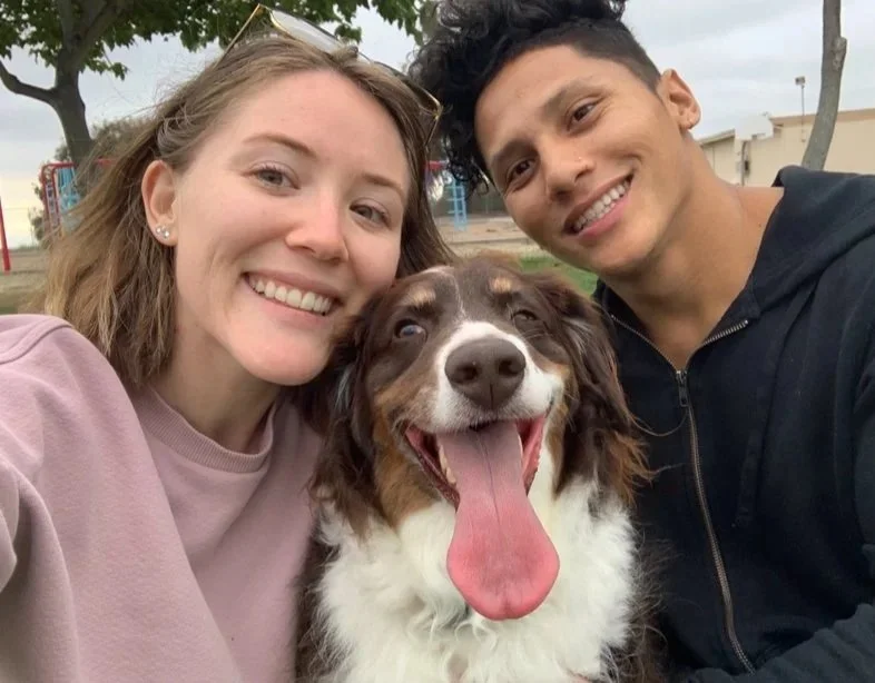 A happy couple and their dog enjoying a day outdoors at a park.