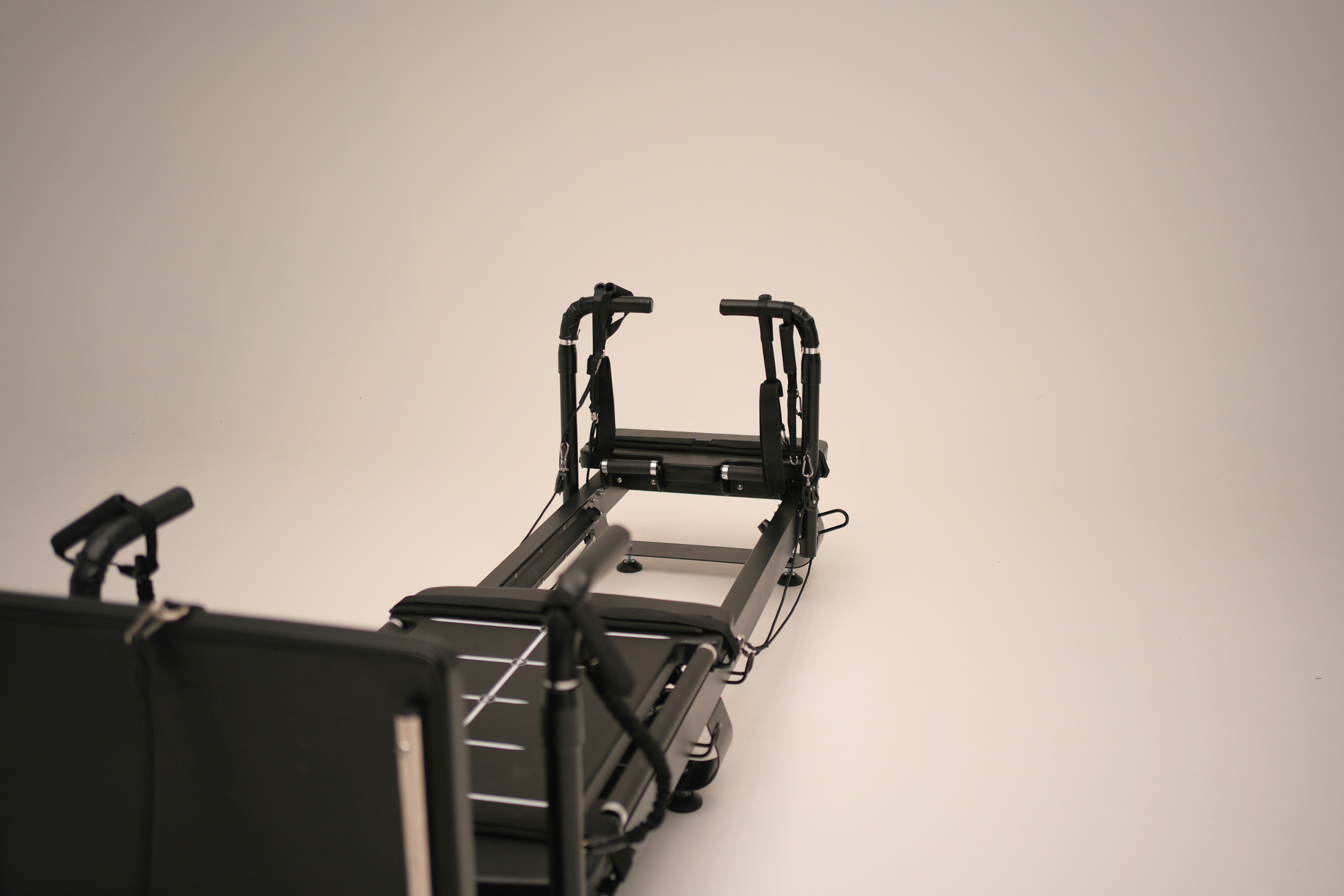 A black sculptformer reformer with a sleek modern design, viewed from an angle against a plain light background.