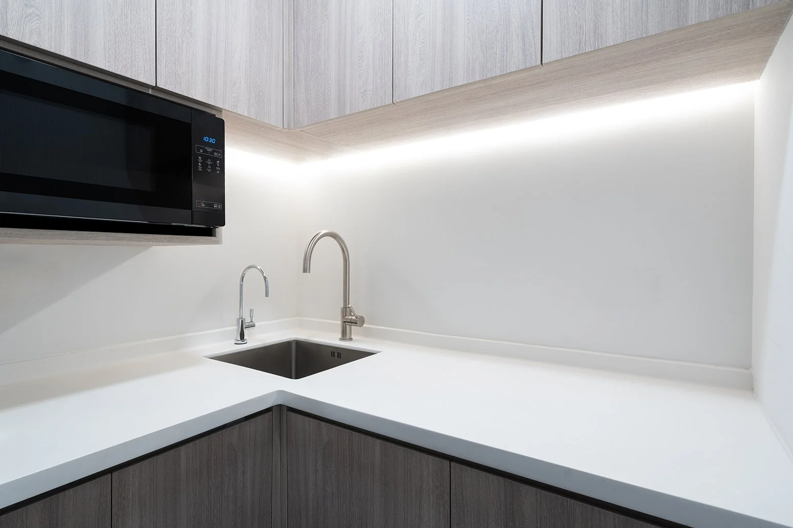 Panthevm Partners office by Wan Fang Construction showing pantry corner with light wood cabinets, under-cabinet lighting for a bright workspace in Hong Kong, Central.