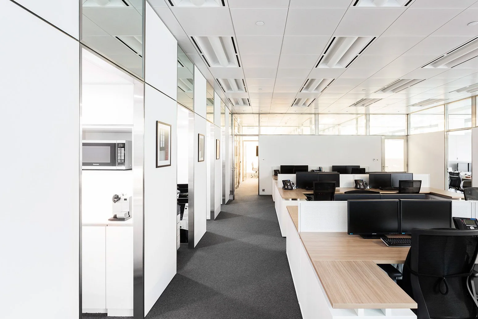 BBO office by Wan Fang Construction showing modern workspace with wooden desk, black mesh chairs, large windows and a minimalist, clean atmosphere in Hong Kong Central.