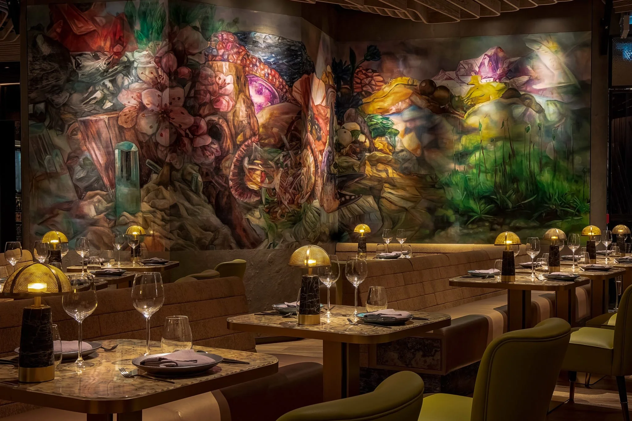 ICHU, an elegant restaurant interior by Wan Fang Construction, showing round marble tables, green chairs, and a high-backed green booth with a colorful abstract wall color painting, Hong Kong Central.