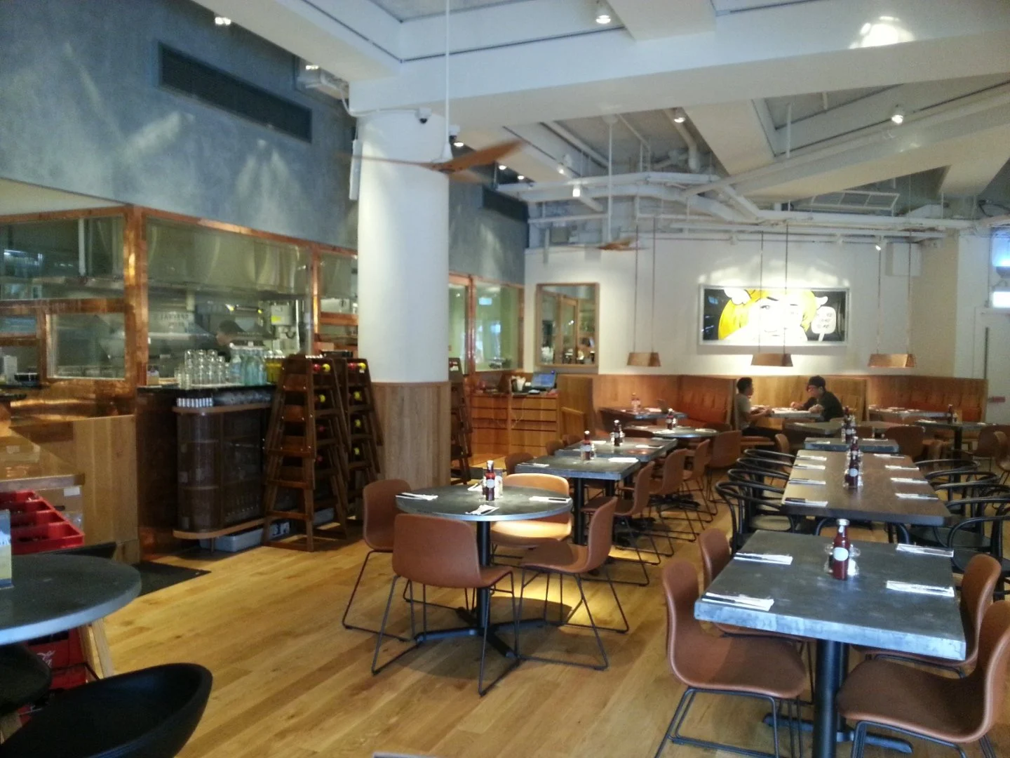 Beef & Liberty, a gourmet burger restaurant in Stanley Hong Kong by Wang Fang Construction, features a modern interior. The space has an exposed ceiling with recessed lighting and fans over polished hardwood floors. Long communal tables with leather 