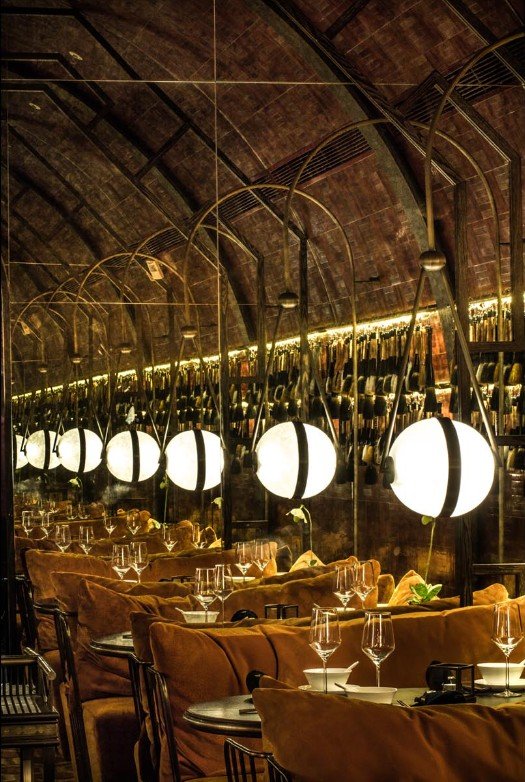Mott 32, an award-winning Chinese Restaurant, interior dining area by Wang Fang Construction, featuring its signature elegant oval-shaped ceiling. The space is furnished with rustic sofas, and its walls are adorned with Chinese brush art, in Hong Kon