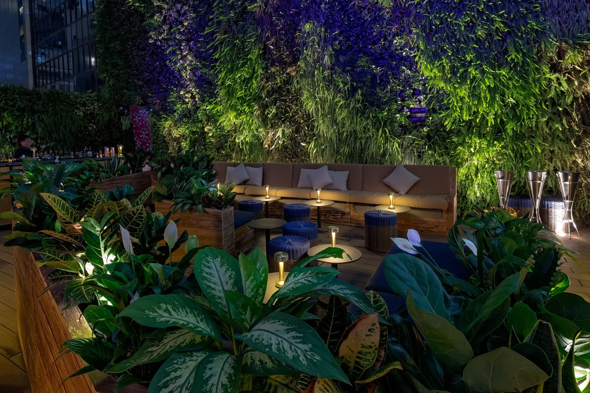 ICHU, an elegant restaurant and rooftop terrace by Wan Fang Construction, a modern rooftop terrace features vibrant vertical garden of purple and green foliage that creates a striking backdrop. Contemporary, neutral-toned furniture and large umbrella
