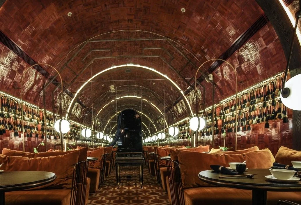 Mott 32, an award-winning Chinese Restaurant, interior dining area by Wang Fang Construction, featuring its signature elegant oval-shaped ceiling. The space is furnished with rustic sofas, and its walls are adorned with Chinese brush art, in Hong Kon