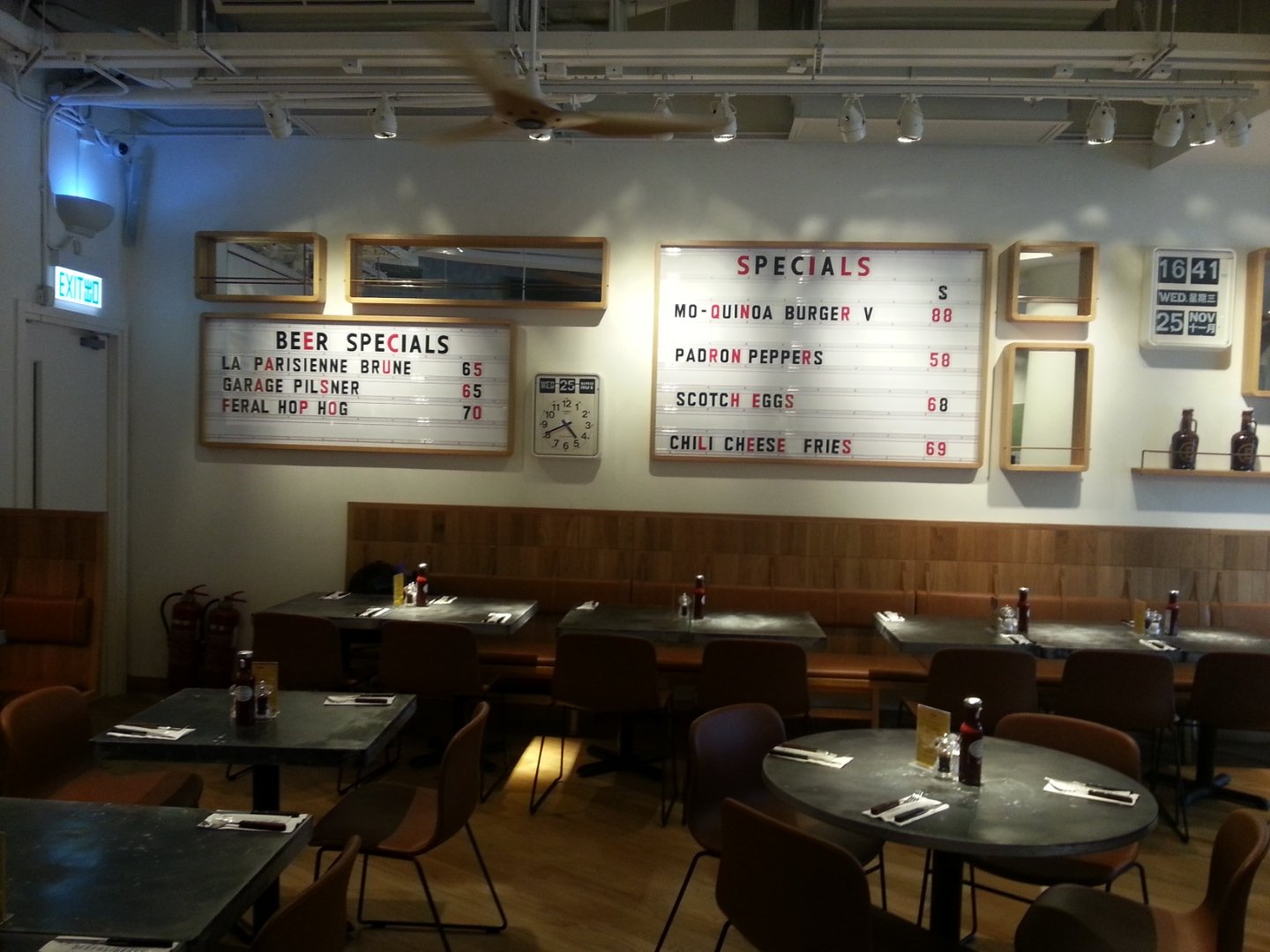 Beef & Liberty, a gourmet burger restaurant in Stanley Hong Kong by Wang Fang Construction, features a modern interior. The space has an exposed ceiling with recessed lighting and fans over polished hardwood floors. Overall neutral color scheme is ac