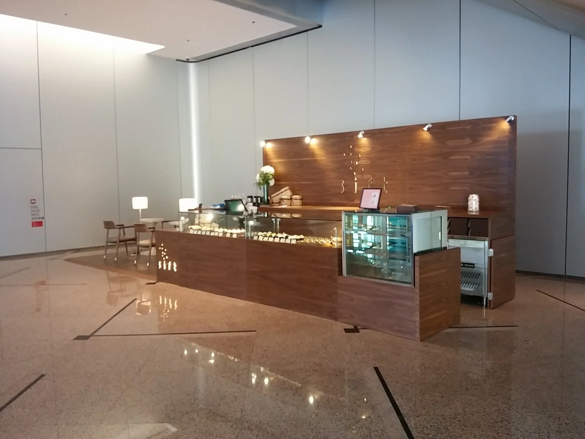 Sift, a modern patisserie in Quarry Bay Hong Kong by Wang Fang Construction, features a clean, inviting interior. A wooden counter with a glass display case showcases various pastries and desserts. 