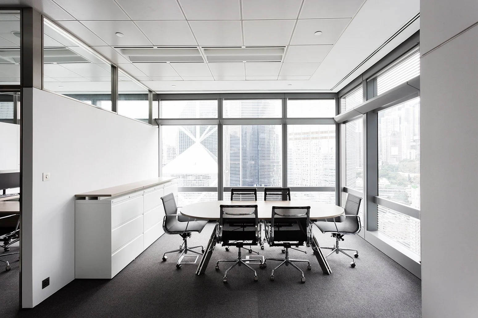 BBO office by Wan Fang Construction showing modern workspace with wooden table, black mesh chairs, large windows and a minimalist, clean atmosphere in Hong Kong Central.