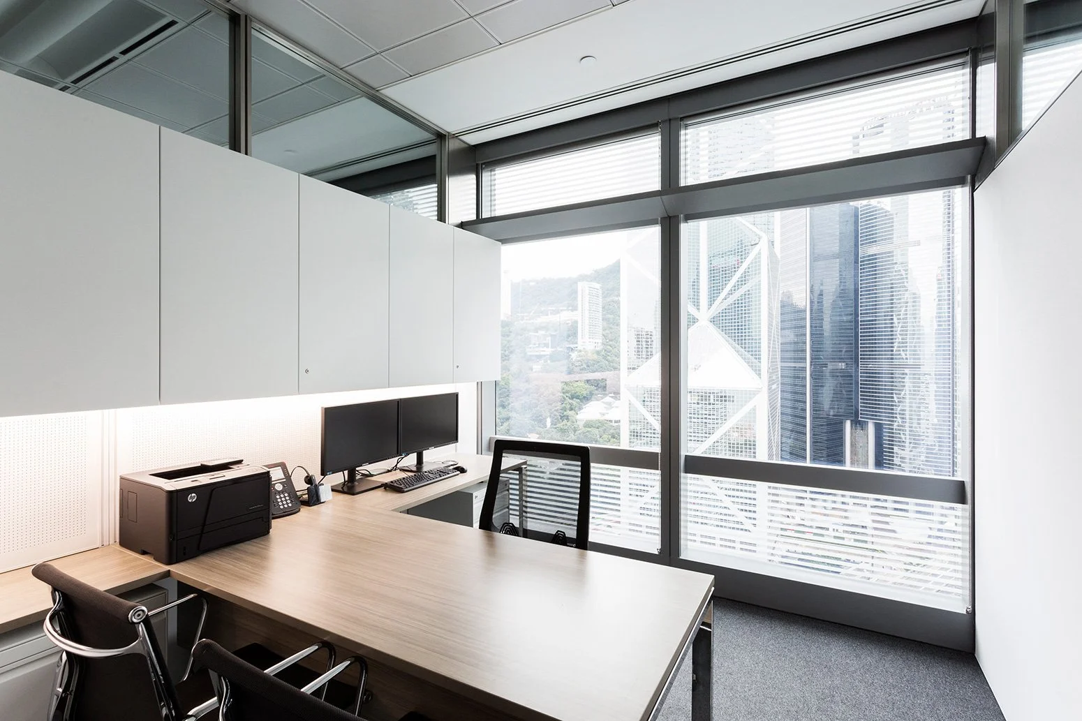 BBO office by Wan Fang Construction showing modern workspace with wooden desk, black mesh chair, large windows and a minimalist, clean atmosphere in Hong Kong Central.