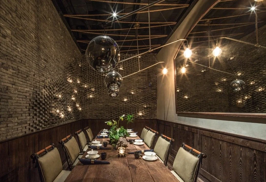 Mott 32, an award-winning Chinese Restaurant, interior private dining room by Wang Fang Construction, featuring a long dark table set for dining, and a mix of modern and rustic decor, in Hong Kong Central. 
