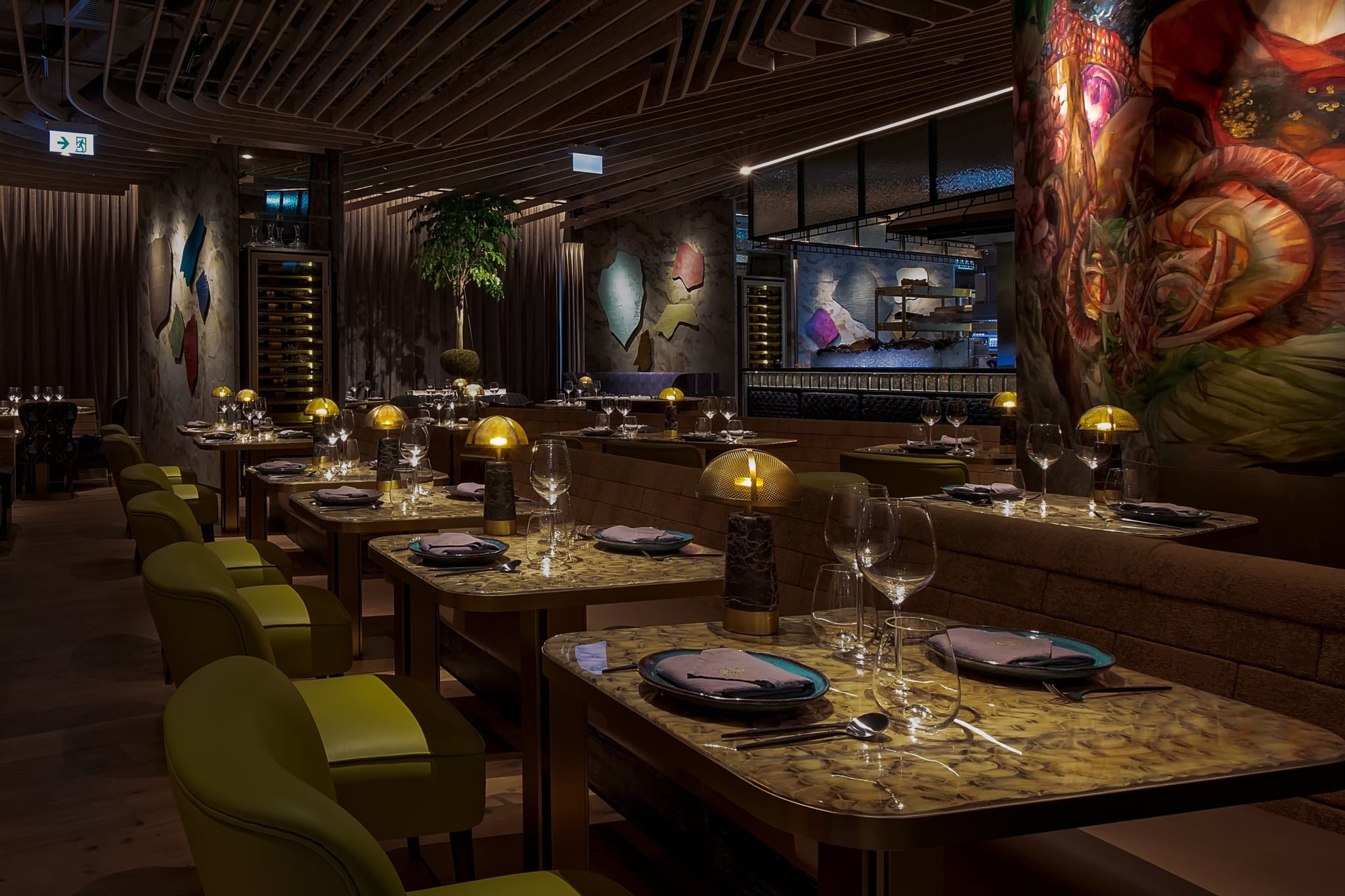 ICHU, an elegant restaurant interior by Wan Fang Construction, showing round marble table and green chairs with a colorful abstract wall color painting, Hong Kong Central.