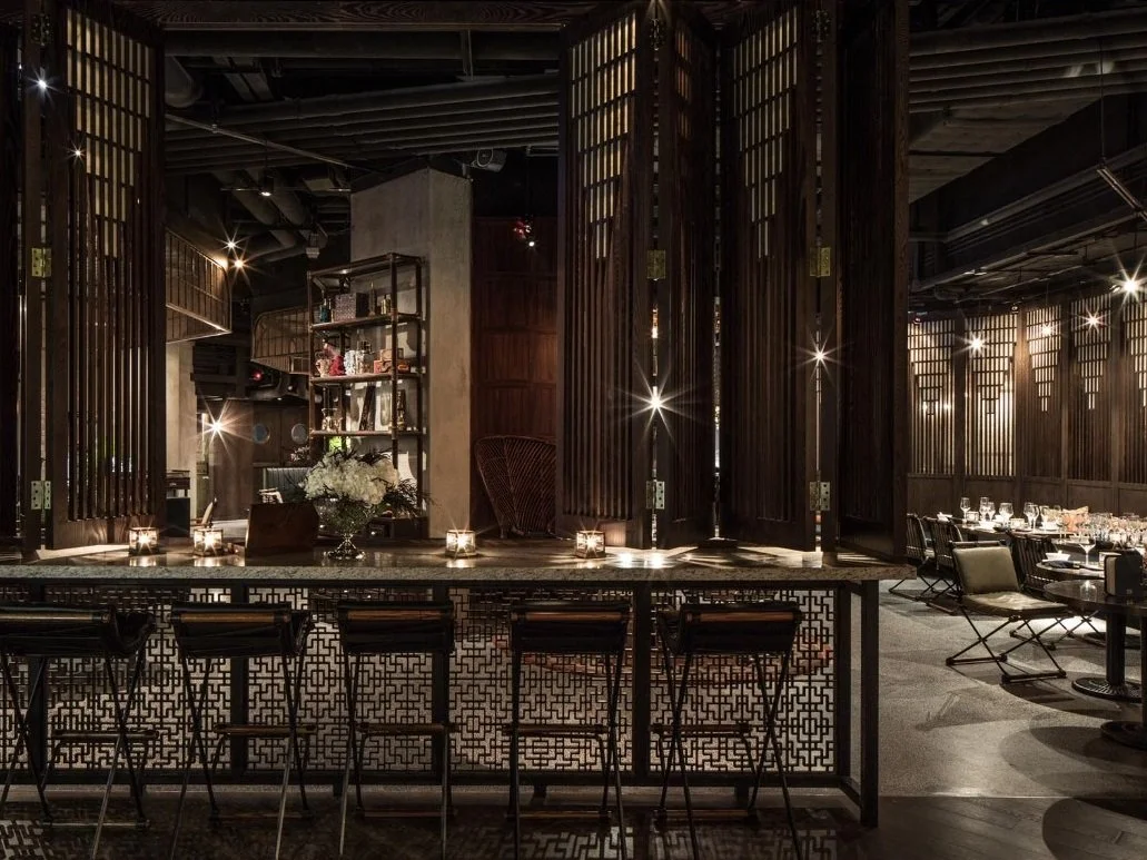 Mott 32, an award-winning Chinese Restaurant, interior dining area by Wang Fang Construction, featuring high chair seating and a mix of modern and rustic decor, in Hong Kong Central. 